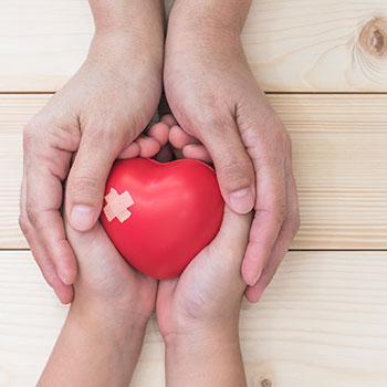 Doctor gently holding a red heart model in hands symbolizing congenital heart disease care in newborns