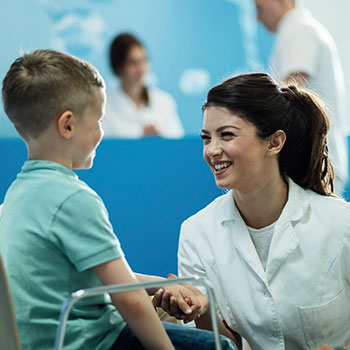 Pediatrician smiling and interacting with a young boy during routine outpatient consultation in a child-friendly clinic